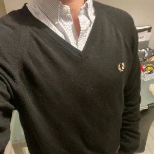 Fred Perry V-Ringat - Jätte grischig🌟 sweatshirt som kommer göra dig mycket stilig i vardagen. Modellen i bilden är 178Cm. Tröjan är som ny och har inga defekter då den har bara använt ett få gånger. Original priset på tröjan är 1299kr men säjer den för enbart 399kr.