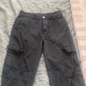 Cargo byxor  - Svarta cargo byxor från pull and bear köpta i spanien, inte min stil längre. Haft på mig de 2 gånger förr. De är storlek 40 men jag som är i storlek 38 passar perfekt. Köpta för 450 kr 