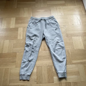Grå Nike tech byxor - Riktigt bra skick, size medium, begagnade.