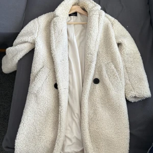 Lång teddyjacka - Lång mysig teddyjacka från Bershka i storlek XS. Är 1,60 men passar nog alla. Använt fåtal gånger, men har inga märken eller slitningar. Köptes för 800kr, säljs för 200kr.   Varm till hösten och vintern. Den är cremefärgad och inte helt vit. 