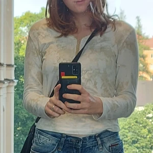 Vit och beige mönstrad tröja - En jättefin långärmad tröja med vit och beige tie dye mönster och tryck. I t-shirt matrial med virkad kant. Står storlek large men passar som en M.