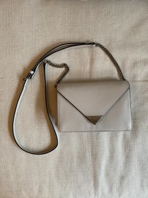 Rebecca Minkoff - Hej!   En Rebecca Minkoff väska som jag köpte för att använda som clutch till min bal eftersom den hade avtagbara rem. Knappt använd och i väldigt fint skick. Är i en väldigt fin grå beige färg. På insidan finns korthållare och en dragkedja. 🥰