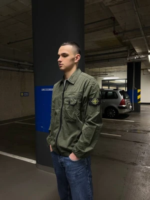 Stone Island Overshirt  - Detta är Stone Island Overshirt - en stilren och praktisk produkt som kommer att höja kvaliteten och stilen på din garderob. Övertröjan är tillverkad av högkvalitativt tyg i muskgrönt färg som kombineras perfekt med olika klädesplagg.