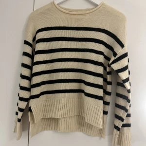 Randig stickad tröja - En randig stickad tröja med slits vid armslutet och på kanterna