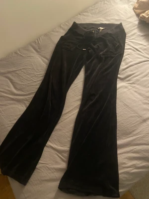 Juicy couture byxor - Svarta juicy couture byxor i en äldre modell. Dem är lågmidjade och i storlek small. Defekt på knapparna där bak då lite av den silvriga färgen försvunnit, annars bra skick. 