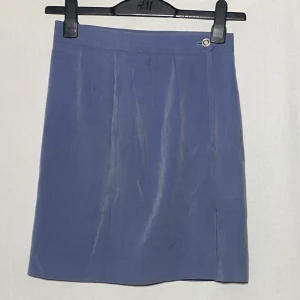 Glansig minikjol med hög midja - Liten slits på sidan som gått upp lite. Går enkelt att sy igen, eller låta det vara lite högre slits. :-) Längd: 49cm  Skicka DM vid frågor. ☆．。･