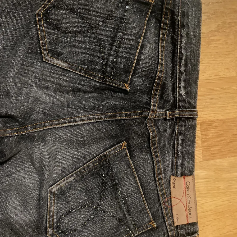  Superfina jeans med låg midja och utsvängda ben fran Calvin Klein. Jätte snygga fickor med paljetter/ glitter. Svarta/gråa💗Skriv för fler bilder💗Storlek W: 28 🫶Skriv för mått!. Jeans & Byxor.