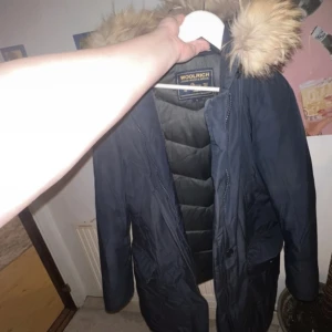 Woolrich Jacka  - Använd, därav billigt pris. Finns små söndriga delar, skriv till mig så skickar jag bild. Äkta dun och äkta päls! Inköpt för 10k på NK 2016.
