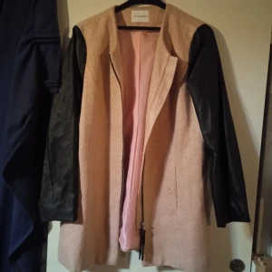 Junarobe - Kappa i ganska grovt tyg som kan komma sig gott nu i kallare årstider. Ärmarna bryter av då de är i syntetskinn och blir en snygg kontrast mot det gulliga ljusrosa .  Gott skick.