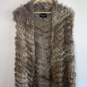 Hollies Stockholm pälsväst - nyskick - En jättefin och något längre väst i äkta kaninpäls, bara använd ett fåtal gånger. Passformen skulle jag säga är onesize trots att strl är XL, detta vill jag påstå enbart påverkar längden på västen. 