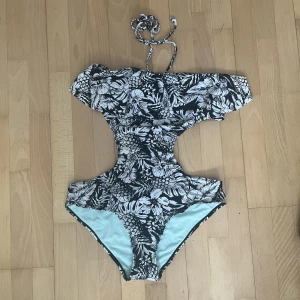 Baddräkt, mönster (svart/vit) - Svart/vit baddräkt. Framhäver höfter & byst på ett riktigt najs sätt. ”Klick”-knäppe bak på rygg, snörning från mitten av bysten, runt nacken. Volang över bysten. Utskuret på sidorna av midjan och bak på ryggen ser det ut som en bikini. 