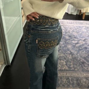 Låga bootcut jeans  - Säljer dom här sjukt snygga jeansen, köpt på marknad på Mallorca! Lågmidjade med coola detaljer. Lite stor i midjan på mig därför säljer jag :(💕 jag har vanligtvis xs i jeans och dessa är s!