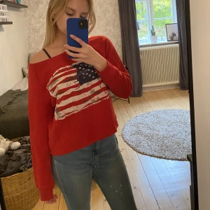 Långarmad tröja  - Röd Långarmad tröja med USA flagan på framsidan och en dragkedja i nacken. 