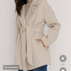 Kort kappa - Beige kappa från nakd stl 36. Inget fel på den förutom lite nopprig som de flesta kappor blir efter lite användning. Ullblandning. Köpt för 699kr