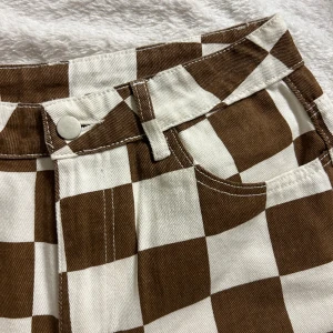 Schackjeans - Bruna schackrutiga byxor från Shein i strl M. De är absolut tunnare än jeans men bra kvalite för att vara Shein. Endast provade men var för små så de är aldrig använda.