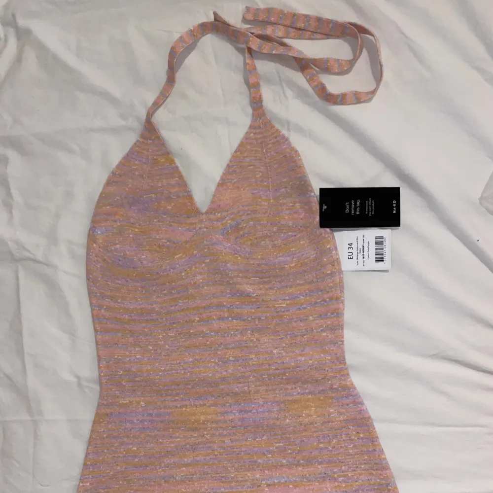 En miniklänning i halterneckmodell från nakd i en rosa färg med tutch av ljusorange. Storlek 34. Orginalpris: 469kr. Säljer då den var för liten.. Klänningar.