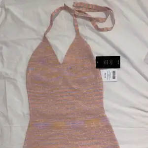 En miniklänning i halterneckmodell från nakd i en rosa färg med tutch av ljusorange. Storlek 34. Orginalpris: 469kr. Säljer då den var för liten.