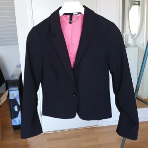 Svart kavaj - Snygg svart kavaj med rosa insida, använder den inte längre så försöker få sålt den istället <3  Tror bara den blivit använd en gång