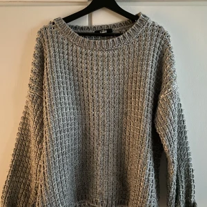 Stickad tröja - Glesstickad tröja i grått och vitt  Tjockare material  Oversized  Storlek L  Använd med vissa tecken av användning däribland men maska på ena axeln när halsringen som släppt  Trots detta är det här den perfekta sensommar tröjan ☀️