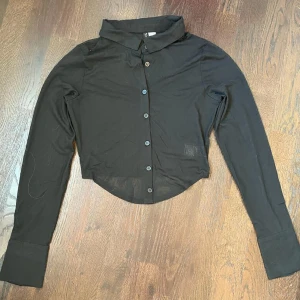 Svart mesh blus - Svart croppad blus från hm som är lite see through. Superfin med en blus eller linne under. Den främre delen är lite längre. Kontakta gärna gör fler bilder eller frågor.