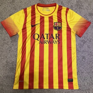 Barcelona fotbollströja - FC Barcelona bortatröja från 2013/2014 säsongen med Messi 10 på ryggen. Tröjan är i färgerna gult och rött som motsvarar de katalanska färgerna och Katalonien som betyder mycket för klubbens kultur. Tröjan är i väldigt bra skick, pris kan diskuteras.