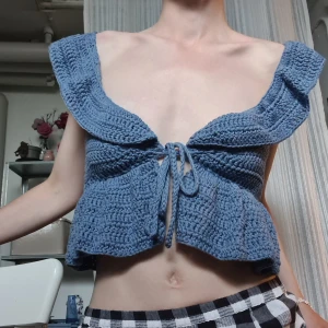 Volangtopp - Virkad volangtopp i blå färg med rosett därfram! 