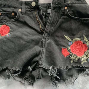 Svarta jeansshorts - Svarta jeanshorts med två blommor på Frakt 29kr med postnord eller instabox 