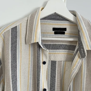 Skjorta (herr) - Skjortan har en oversized fit. Den är av 100% bomull, går att ha i både varmt och kallt väder.