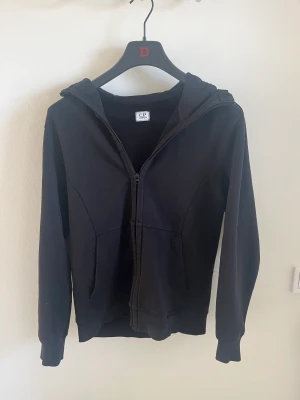 CP Company hoodie - Jag säljer nu min CP Company hoodie för att den är för liten för mig. Storleken är L men skulle säga att den passar mer som en M. Skicket är 8/10 då bandet på zipen har jag tagit bort men medkommer vid köp. Priset är inte hugget i sten!! 