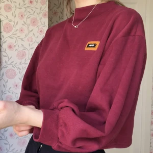 Vinröd tröja med ballong ärmar  - Trekvartslånga ärmar med mycket volym och hög krage. 