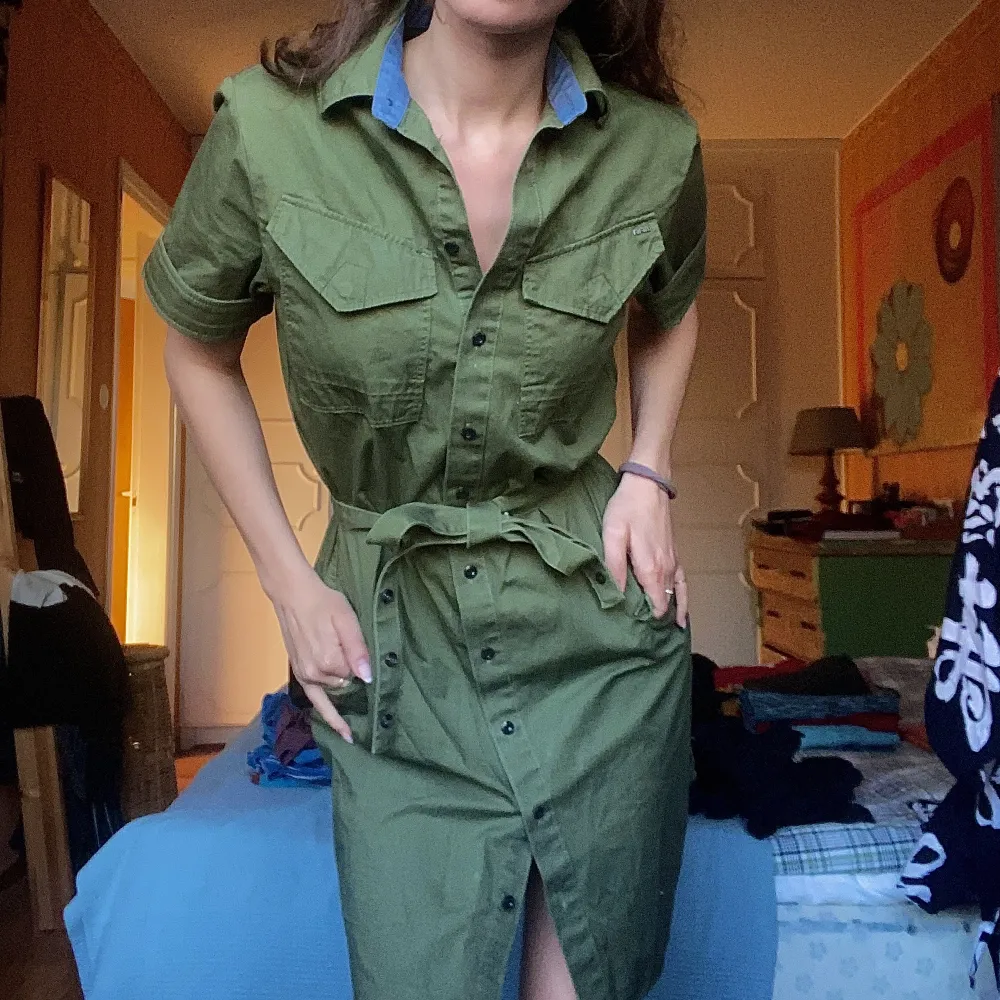 En klänning i cargostil.  Jag är 168 cm lång. Klänningen slutar straxt över knät Militärgrön Orginalpris 900. Klänningar.