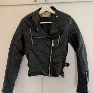 Bikerjacka strl 36 - Fin bikerjacka i strl 36. Liten storlek snarare en 34. Fint skick ser nästan oanvänd ut. Skinnimitation