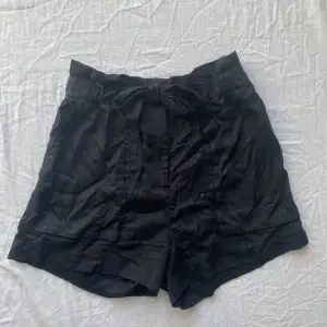 Shorts i tyg med knytdetalj på framsidan och långa fickor. Blixtlås och knapp. 