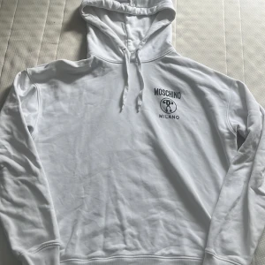 Moschino milano hoodie - Fett Moschino milano hoodie som är använd ett fåtal gånger, skick 9/10 då den har någon prick som går att få bort i tvätten, nypris 2800