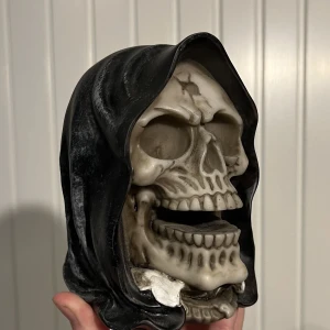 dödskalle dekoration - en dödskalle med luva ☠️den är gjord av trä och är ungefär 12 cm lång. jättecool som dekoration i ditt rum eller som halloween dekoration 🦴