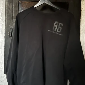Sweatshirt (PEAK PERFORMANCE)  - Fin svart sweatshirt från Peak. Den har vissa tecken på användning (främst att den är litet blekt kring kragen, se bild 3). Logga i svart på framsidan, ser inte ut att vara använd mer än fyra fem tvättar. 