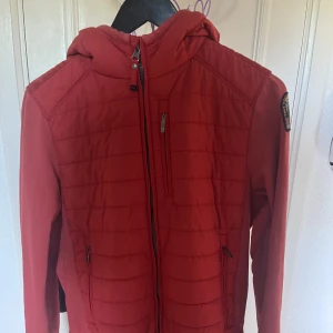 Röd Parajumperjacka barnstorlek 170  - Säljer nu min parajumper jacka eftersom den har blivit förliten. Jackan i sig är riktigt bekväm och rätt varm jacka under våren/hösten. Jackan passar perfekt för dig som är 160-170. Priset kan diskuteras vid snabbaffär. Nypris 2499.