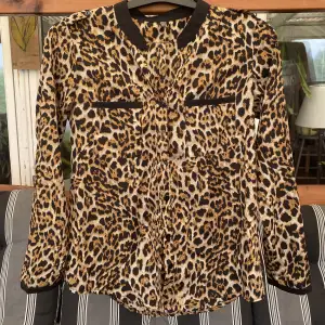 En skjorta med leopardmönster, har detaljer på axlarna se bild två. 