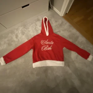 Jul hoodie - En röd/vit jul hoodie från HM 🫶 Hoodien har en luva och ett tryck på framsidan där det står ”santa babe” ❤️ Skriv privat för mer frågor