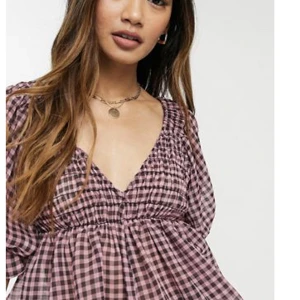 Volang topp - Söt volangtopp från Asos. Rosa och svart rutig. Smockad runt bysten och puffärmar som gör den så söt. Storlek 40 men skulle säga att det är en M😊. Använd bara ett fåtal gånger så i princip nyskick💕