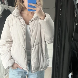 Puffer jacket  - Grå/beige dunjacka från H&M divided, färgen ser mer ut som bild 1 än 2 och 3. Använd ett fåtal gånger, inga defekter. Tycker den är skitsnygg men har en annan liknande som sitter bättre så den kommer aldrig till användning 