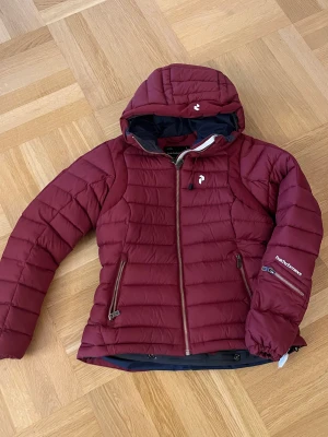Peak skidjacka som ny - Peakjacka i vinröd färg. Med snölås och i absolut nyskick