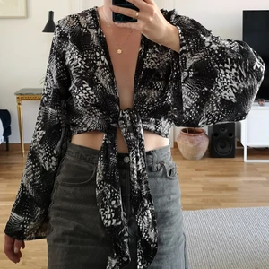 Omlottblus från H&M i storlek XS - Mönstrad omlottblus från H&M i storlek XS, kan antingen knytas som på bilden eller bak i ryggen för att vara lite mer täckande.
