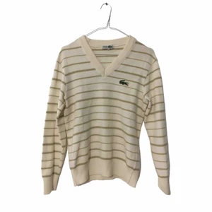 Vintage Lacoste - Vintage Lacoste v-ringad tenniströja / stickad tröja. Ecru vit med khaki ränder. Ull-blandning. Mycket bra vintage skick, har använts men inga uppenbara defekter. Troligen från 70-talet! Köpt i Italien. Passar XXS-S kvinnor eller XXS-XS man.