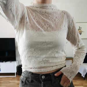 Spetstopp från Lindex i storlek M - Vit skir spetstopp från Lindex i storlek M. Tröjan har långa ärmar och hög hals. Jag på bilden är 170 cm lång och har oftast 36/S i toppar.