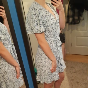 Blå/Vit Blommig Sommarklänning - Sommar klänning med blå/vita blommor med dragkedja på ena sidan. Klänningen är i nyskick och är endast provad.