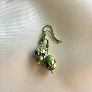 Handgjorda örhängen med emaljerad grön pärla. Aldrig använda.
