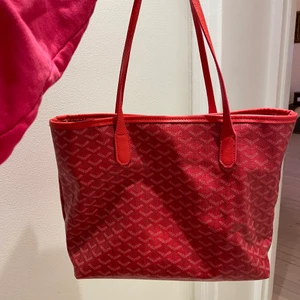 Goyard liknande väska. - Goyard liknande väska. Färg:röd. Ca 30 cm bredd, man får plats med en laptop och annat utan problem. Frakt 66kr.