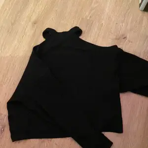 En svart fin tröja som har hål vid axlarna(som det ska vara) 