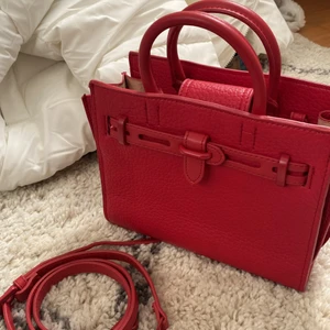 Röd väska MANGO  - En röd väska från MANGO i jätte bra och fräscht skick👜♥️ (mango märket har lossnat på ena sidan i tråden men inget som syns) Jag har endast använt den en gång! Liten men väldigt rymlig väska. Långa bandet är avtagbart och man kan justera längden. Även spännet fram går att justera!  Nypris tror jag ligger på ca 300kr★  skicka meddelande om fler bilder önskas!  (Spårbar frakt) 